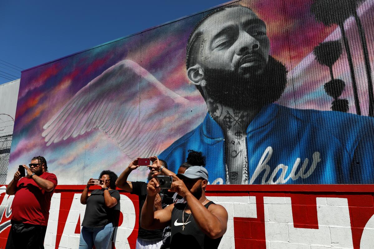 Vitors photograph family and friends where deceased murals of Nipsey Hussle are on display