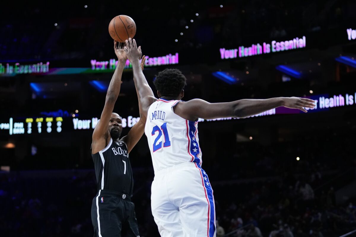 Brooklyn Nets' Kevin Durant, left, goes up for a shot against Philadelphia 76ers' Joel Embiid during the first half of a preseason NBA basketball game, Monday, Oct. 11, 2021, in Philadelphia. (AP Photo/Matt Slocum)