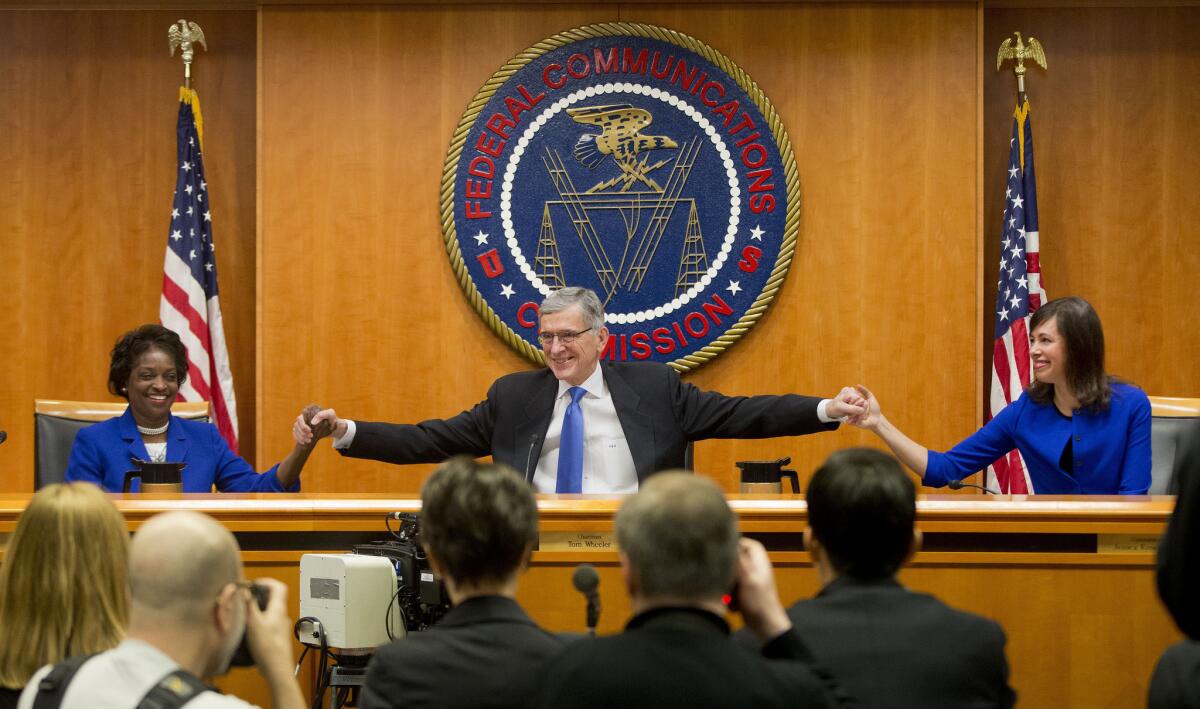 Federal Communications Commission Chairman Tom Wheeler, center, joins hands with commissioners Mignon Clyburn, left, and Jessica Rosenworcel, before a Feb. 26 meeting at which the agency approved net neutrality regulations.
