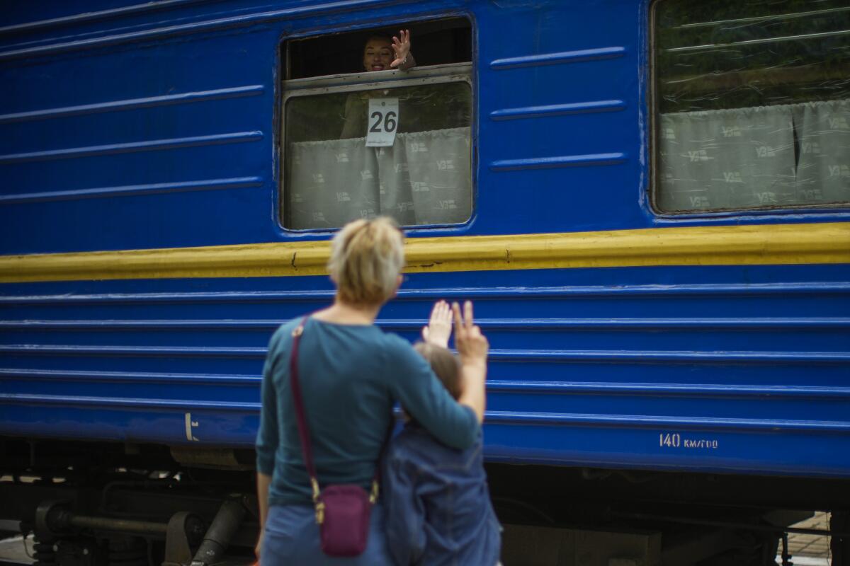Woman and girl waving goodbye to passenger on a train