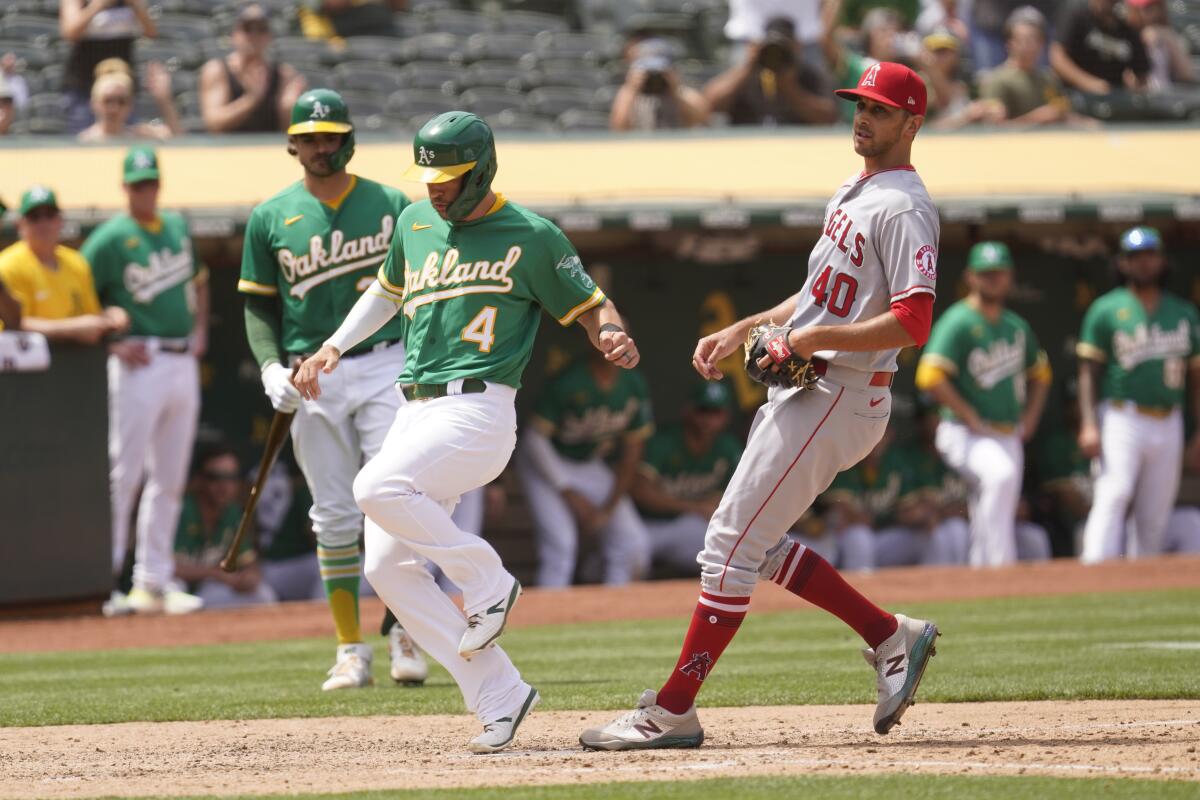 Oakland Athletics' Chad Pinder, left, scores on a wild pitch thrown by Angels relief pitcher Steve Cishek.