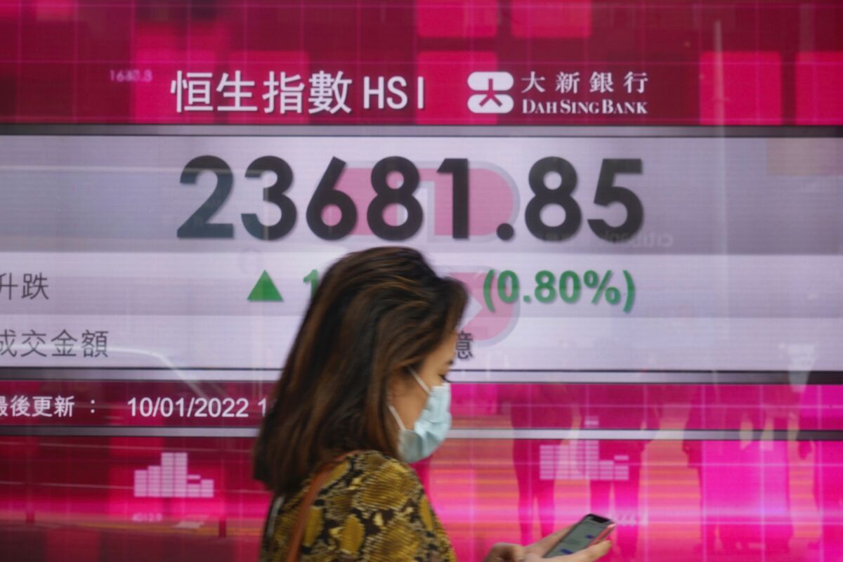 A woman walks past a bank's electronic board showing the Hong Kong share index at Hong Kong Stock Exchange Monday, Jan. 10, 2022. Asia stock markets were mixed Monday after Wall Street fell on worries the Federal Reserve will raise interest rates as soon as March. (AP Photo/Vincent Yu)