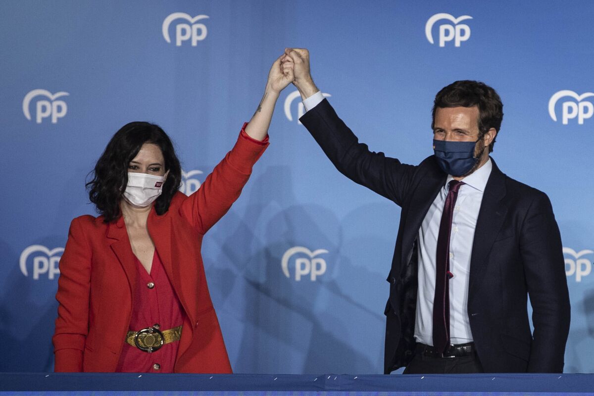 Conservative Madrid regional president Isabel Diaz Ayuso, left, and Popular party leader Pablo Casasdo wave outside the popular party headquarters in Madrid, Spain, Tuesday, May 4, 2021. Madrid residents voted in droves for a new regional assembly in an election that tests the depths of resistance to virus lockdown measures and the divide between left-wing and right-wing parties. Regional President Isabel Díaz Ayuso, who called the early election by dissolving her center-right coalition, had set off to broaden her power base and open up to an alliance with the far-right. (AP Photo/Bernat Armangue)