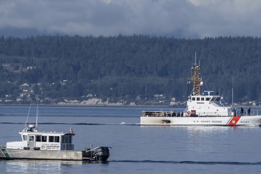 FILE - A U.S. Coast Guard boat and Kitsap, Wash., County Sheriff boat search the area, Sept. 5, 2022, near Freeland, Wash., on Whidbey Island north of Seattle where a floatplane crashed the day before, killing 10 people. The bodies of some of the victims and most of a floatplane have been recovered. Island County Emergency Management confirmed Thursday, Sept. 29, 2022, that multiple bodies were recovered, (AP Photo/Stephen Brashear, File)