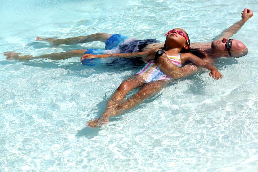 BAKERSFIELD, CA - JULY 17, 2023 - Mariah Barnett, 9, and her father Troy, 38, recline in a pool of cool water while tryng to beat the 109 degree heat at the McMurtrey Aquatic Center in Bakersfield on Monday on July 17, 2023. "Horrible," was the one word used by Troy to sum up the recent heat wave. (Genaro Molina/Los Angeles Times)