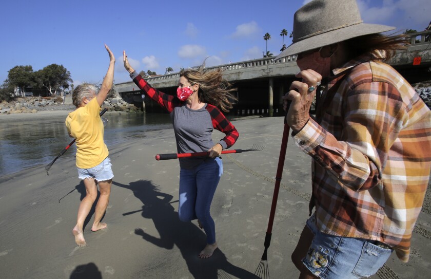 Sharon Belknap, Nadia Quiros Horvath and Heather Nelson dancing while carving a sand mandala at Cardiff State Beach.