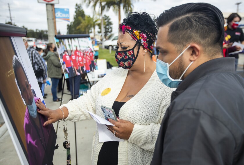 Irene Santos and Matthew Rodriguez look at a photograph of their father, Armando Rodriguez, who died of COVID-19.