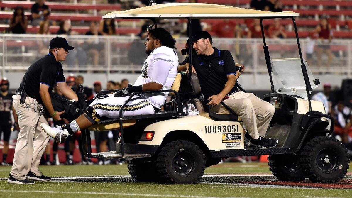 Bruins offensive lineman Tevita Halalilo is driven away after suffering an injury in the final minute of a 37-3 win over UNLV on Saturday night.