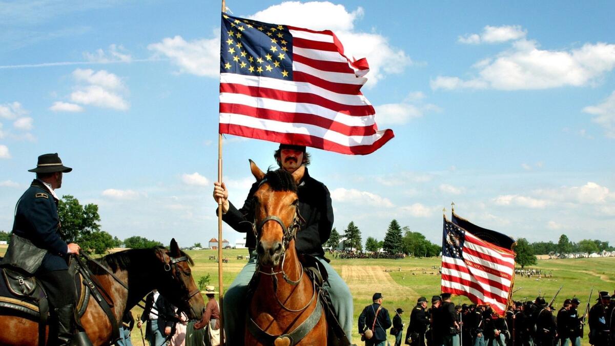 A flag bearer rides behind the Union line during a reenactment in Gettysburg, Pa.