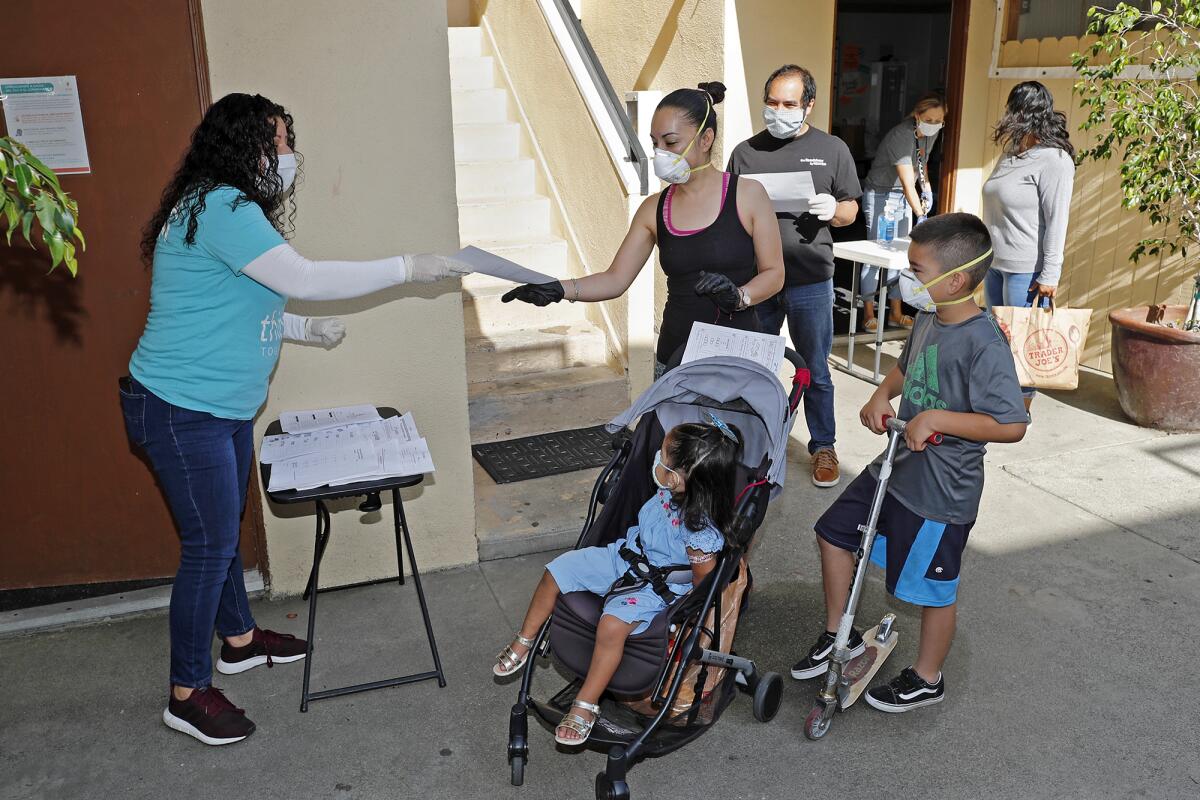 Ruth Malagon hands a learning packet to Sindia Chavez at Shalimar Learning Center.