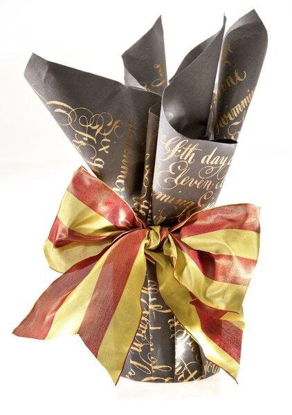 How to make small gift seem special? Start with elegant wrap. Midori's Twelve Days paper spells out the lyrics to "The Twelve Days of Christmas" in black and gold (or red text on green). Here, an $8 candle holder is centered on the wrapping. The paper is pulled up and pleated to conform to the round shape, with the loose ends gathered at the top. To jazz it up: A 2-inch wide striped Promenade ribbon.