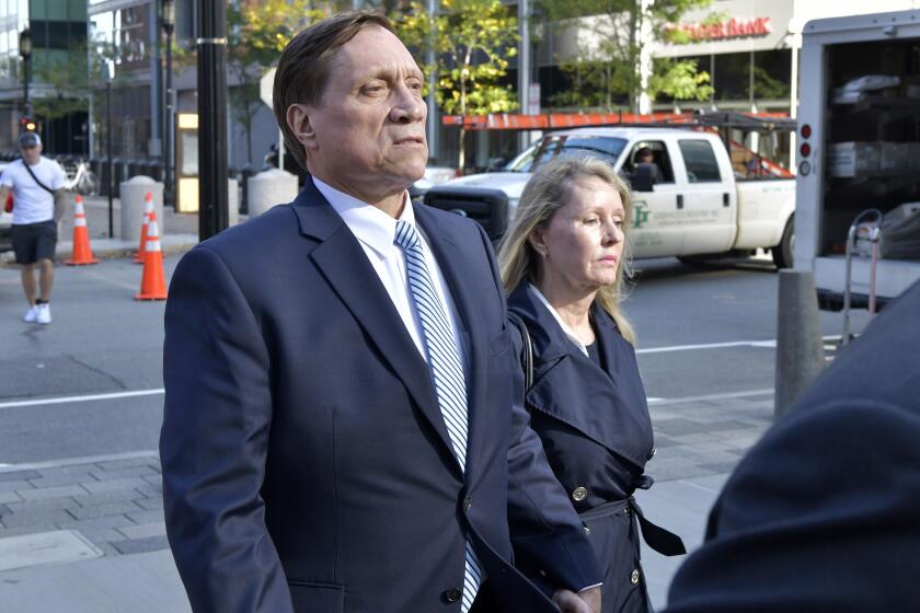 FILE - John Wilson, left, and his wife leave federal court after he was found guilty of participating in a fraudulent college admissions scheme, Oct. 8, 2021, in Boston. The former Staples Inc. executive Wilson, whose fraud and bribery convictions in the sprawling college admissions cheating scandal were thrown out by an appeals court, was sentenced on Friday, Sept. 29, 2023, to six months of home confinement for a tax offense. (AP Photo/Josh Reynolds, File)
