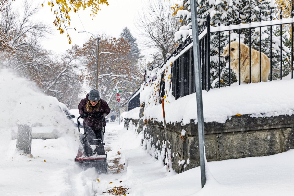 A person clears a snow-covered sidewalk in Helena, Mont.