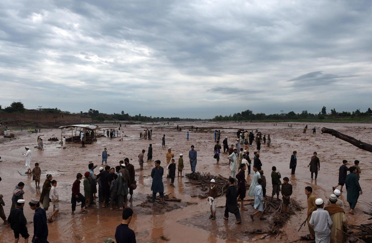 Market vendors and residents walk through the flood waters. (A Majeed / AFP/Getty Images)
