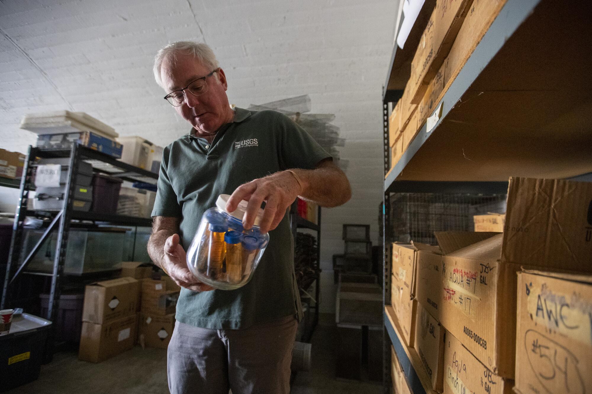 A man holds a jar of insect specimens.