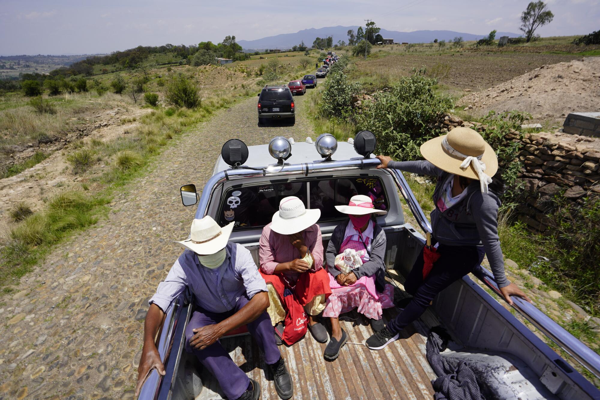 Family members ride on the back of a truck toward the cemetery at El Rincón de San Ildefonso on Thursday.