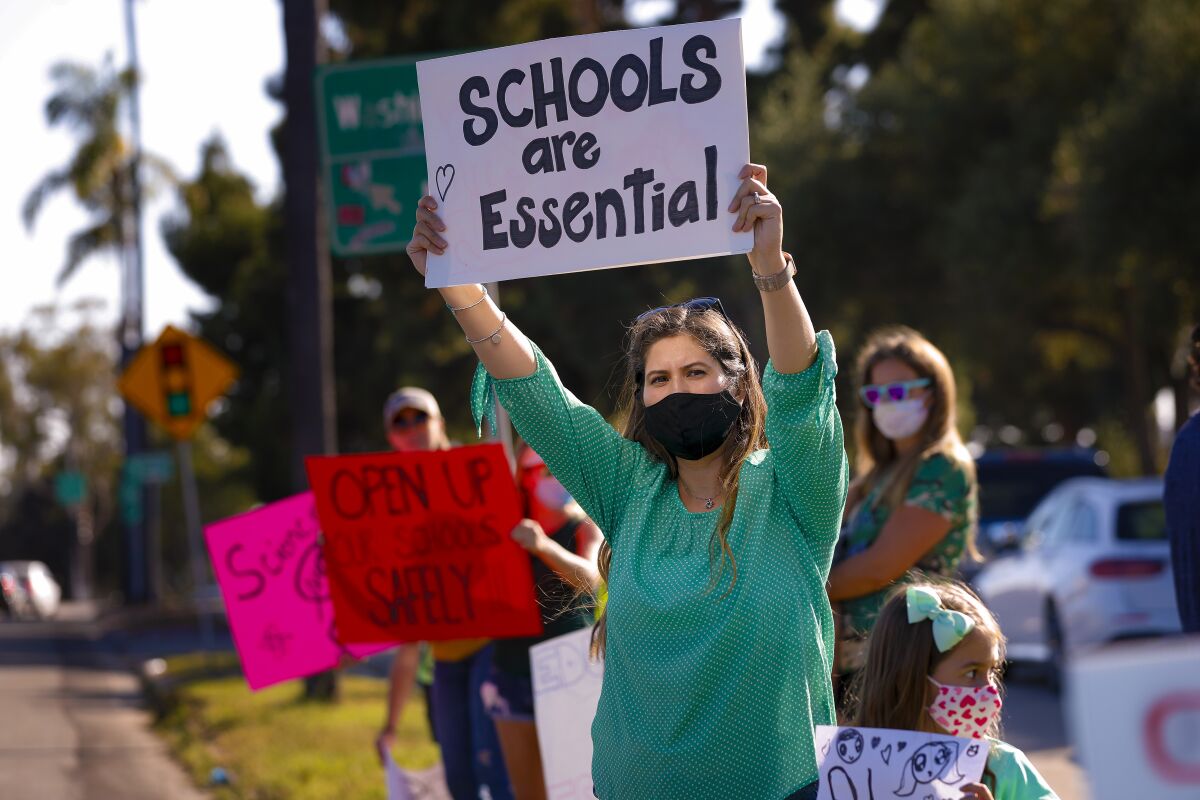 Parents and protesters held signs calling for San Diego Unified schools to reopen in September