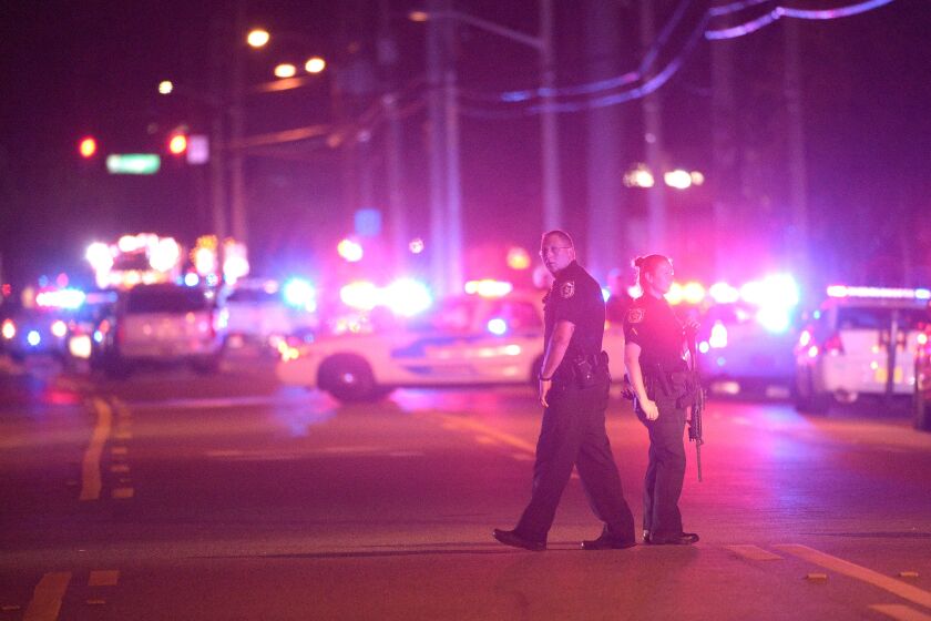 Police officers stand guard down the street from the scene of a shooting that killed at least 50 people and wounded an additional 53 at a nightclub in Orlando, Fla., Sunday.