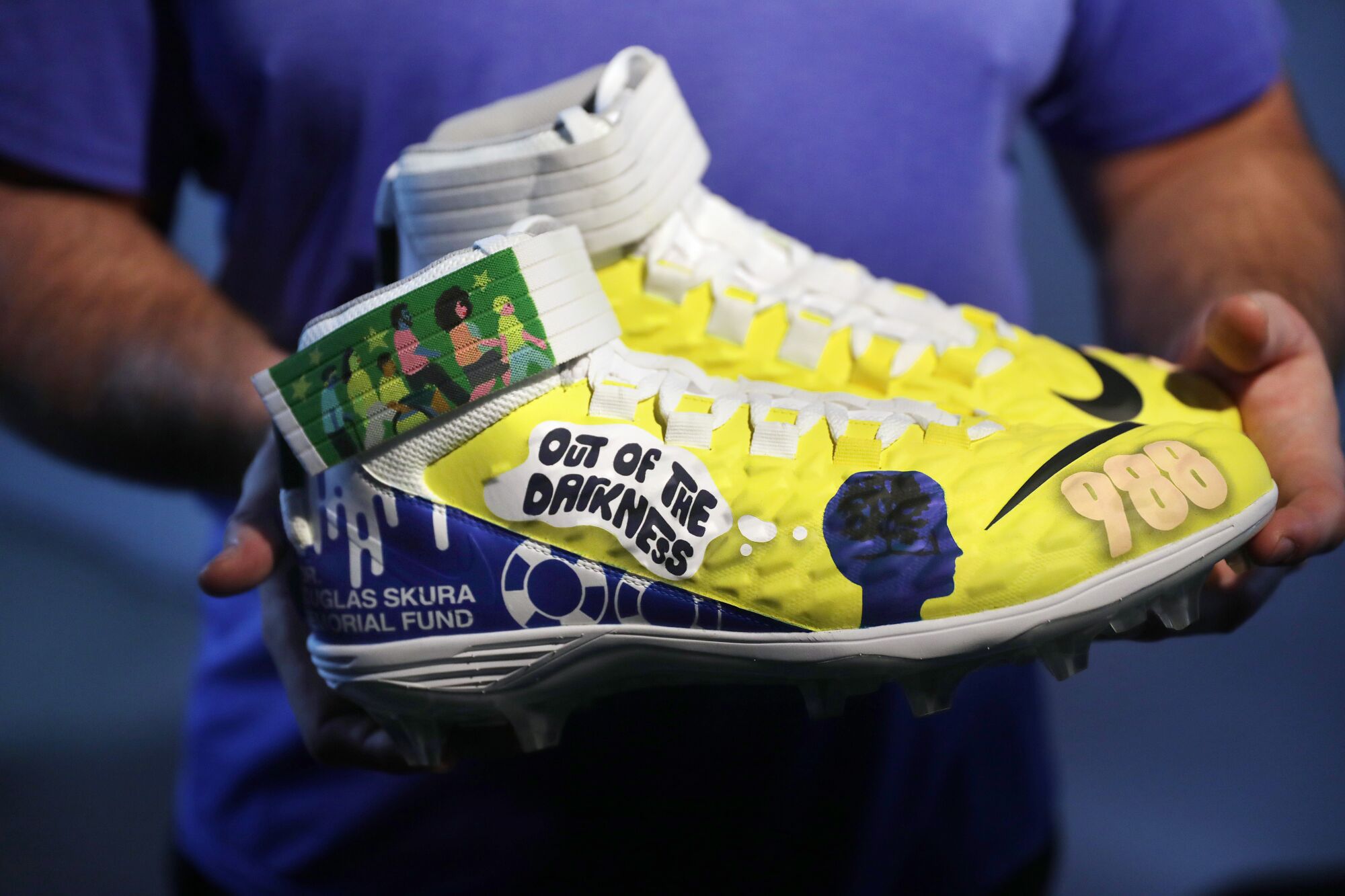 Rams center Matt Skura holds up a cleat honoring his father, who died by suicide last year