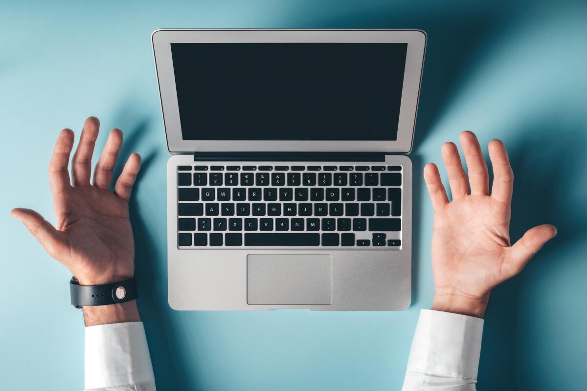 A pair of hands, palms open, flank a laptop. 