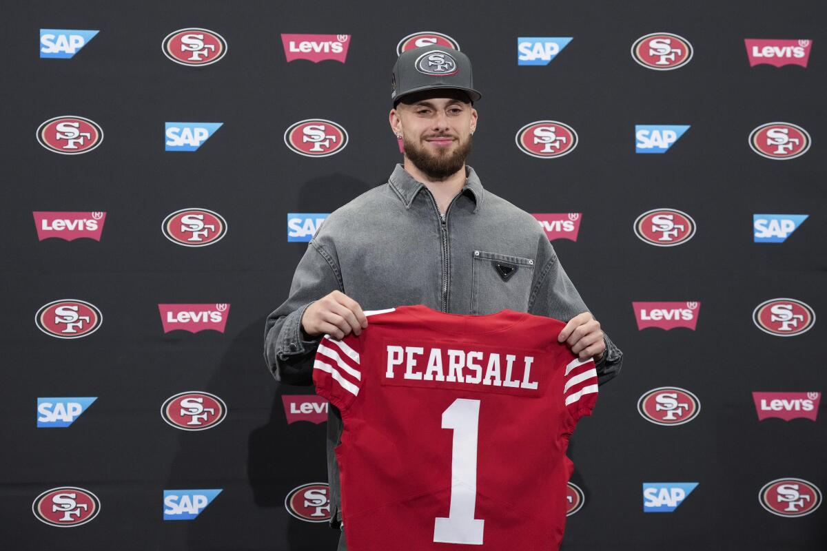 San Francisco 49ers rookie Ricky Pearsall holds a red jersey during a news conference.