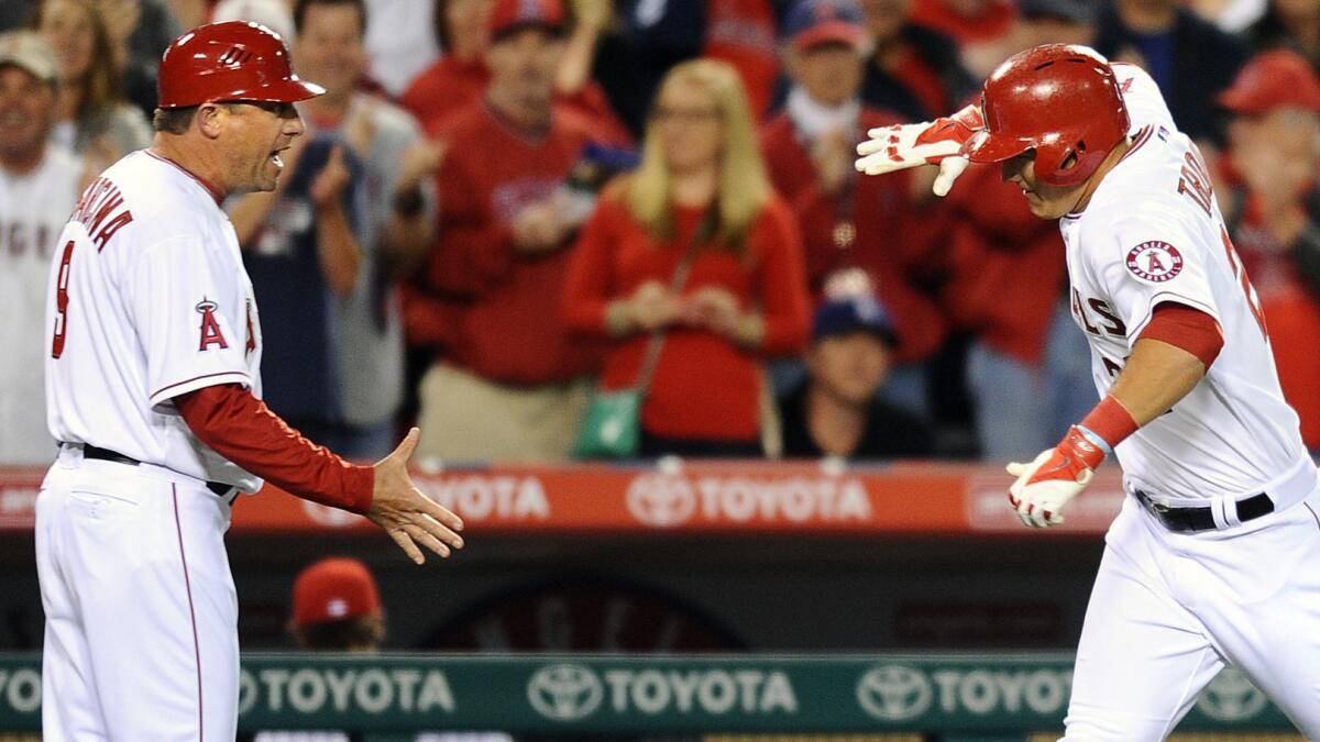 Gary DiSarcina, coaching third base for the Angels, congratulates Mike Trout on a home run against Seattle on March 31, 2014.