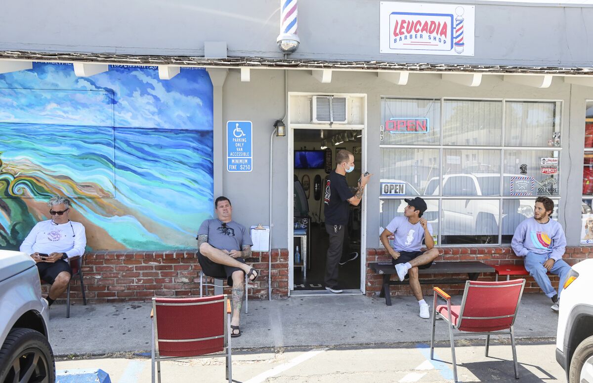 Socially distanced customer sit outside of the Leucadia Barber Shop on May 27, 2020 in Encinitas, California. This was the first day salons have been allowed to reopen since the shutdown.