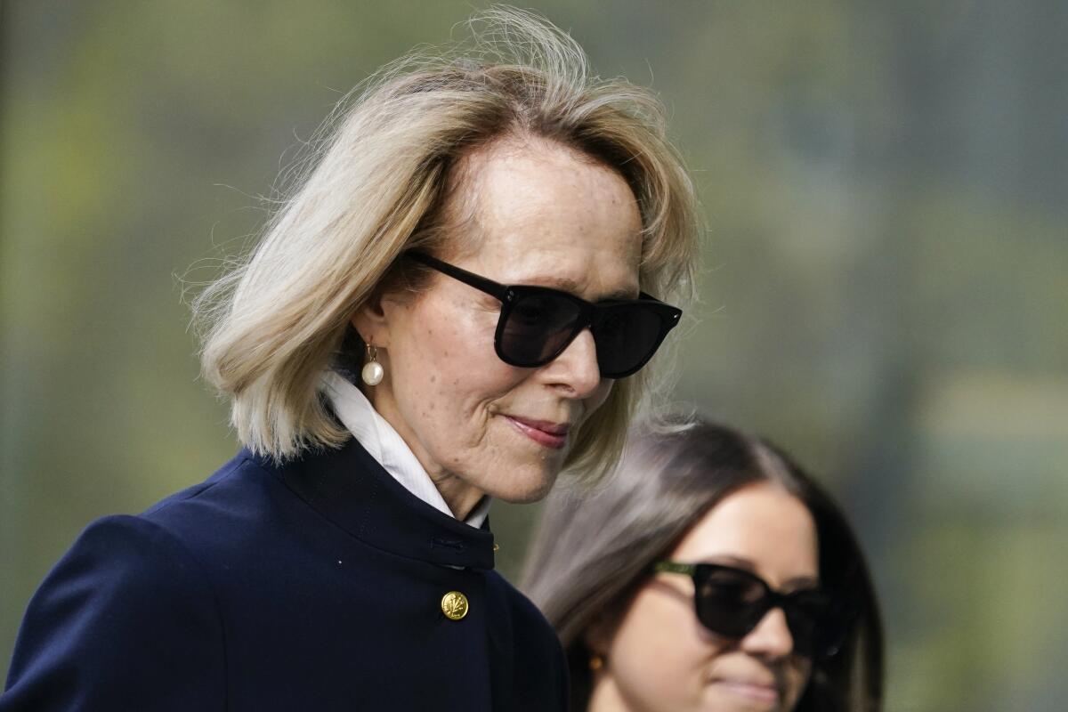 A woman in dark sunglasses and a blue jacket. 