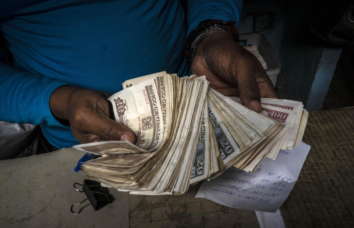 A worker shows a wad of Cuban pesos in Havana, Cuba