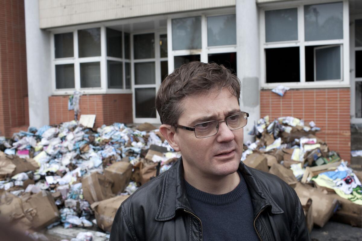 Satirical French newspaper Charlie Hebdo's editor in chief, Charb, answers reporters in front of the headquarters of the newspaper after the office was firebombed Nov. 2., 2011.