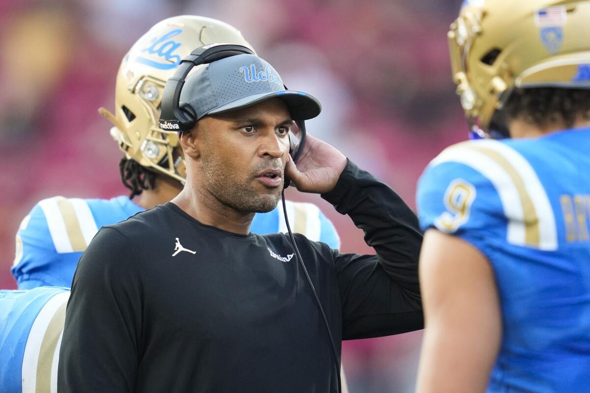 UCLA defensive coordinator D'Anton Lynn talks with linebacker Choe Bryant-Strother during a timeout