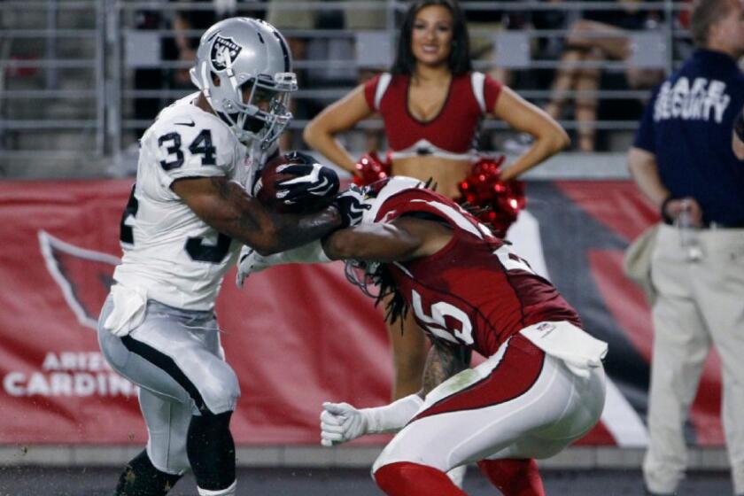 Raiders running back George Atkinson III (34) brushes aside Cardinals defensive back Marqui Christian on a touchdown run a game on Aug. 12.