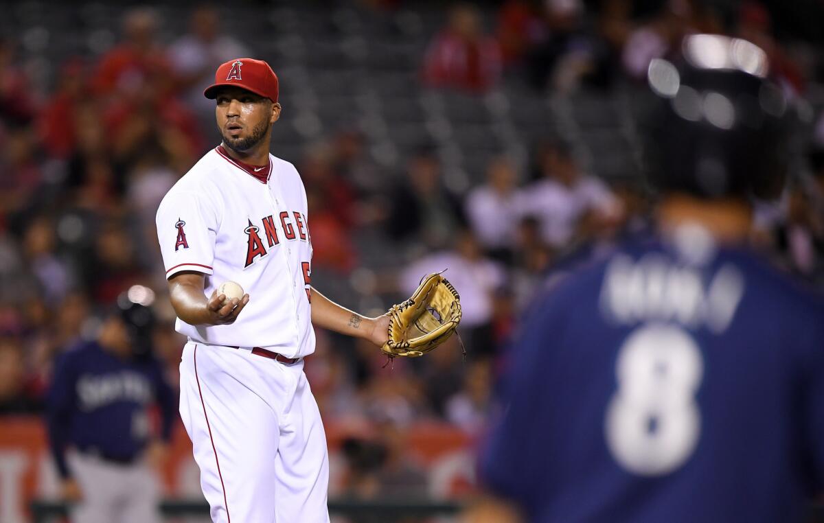 Angels relief pitcher Deolis Guerra, left, reacts after being called for a balk as Mariners outfielder Norichika Aoki stands on first during the seventh inning.