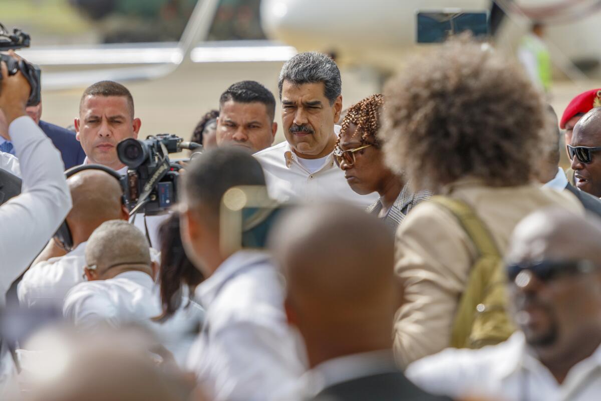Venezuelan President Nicolás Maduro is surrounded by people on an airport tarmac. 