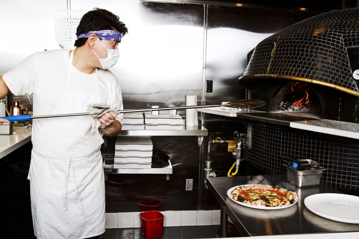A chef mans the wood-burning pizza oven at Pizzeria Sei.