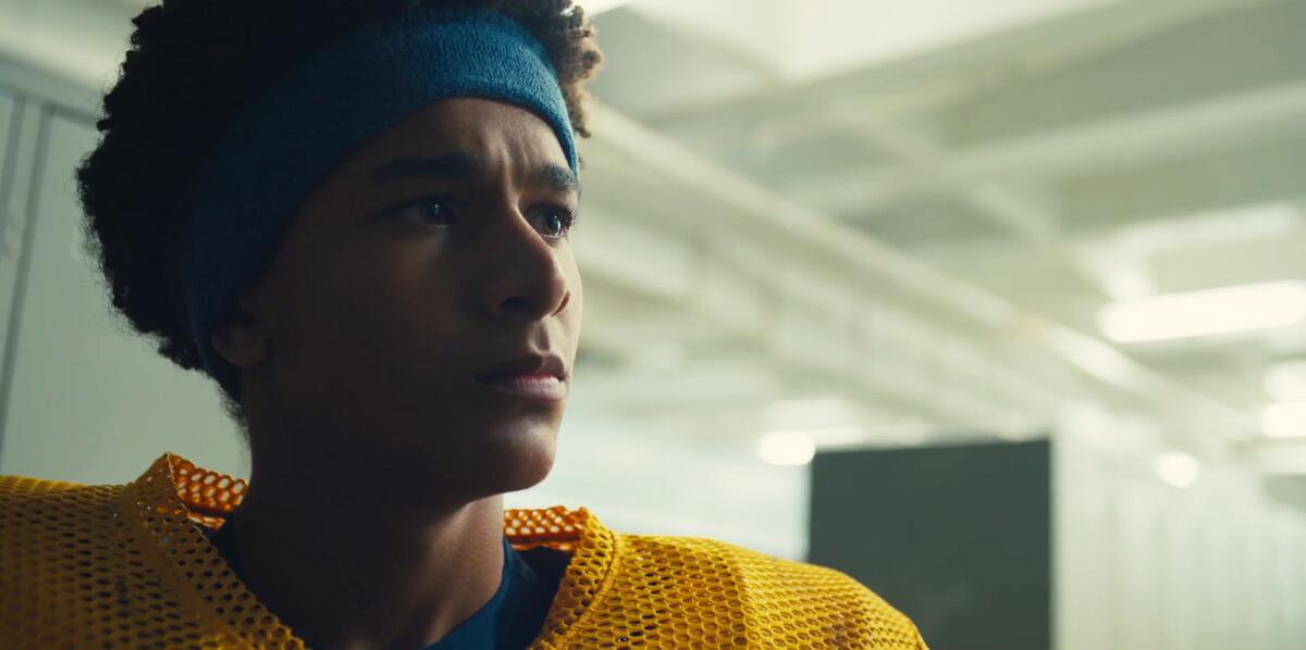 A teenage boy in a blue headband and yellow football jersey.