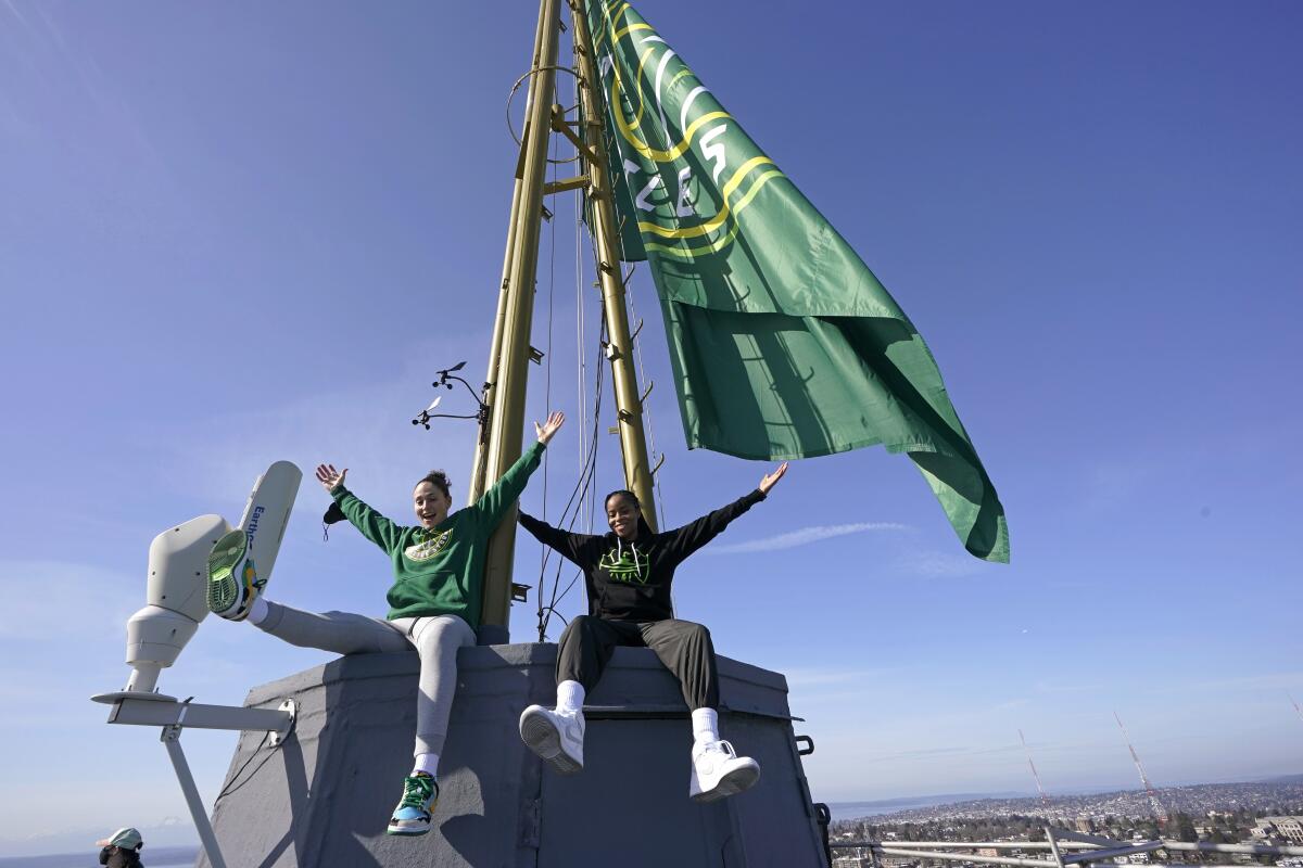 Seattle Storm guards Sue Bird, left, and Jordin Canada pose for photos Wednesday, March 3, 2021, on the roof of the Space Needle in Seattle after they raised a flag with the team's new logo on it. Bird re-signed with the Storm earlier in the week. (AP Photo/Ted S. Warren)