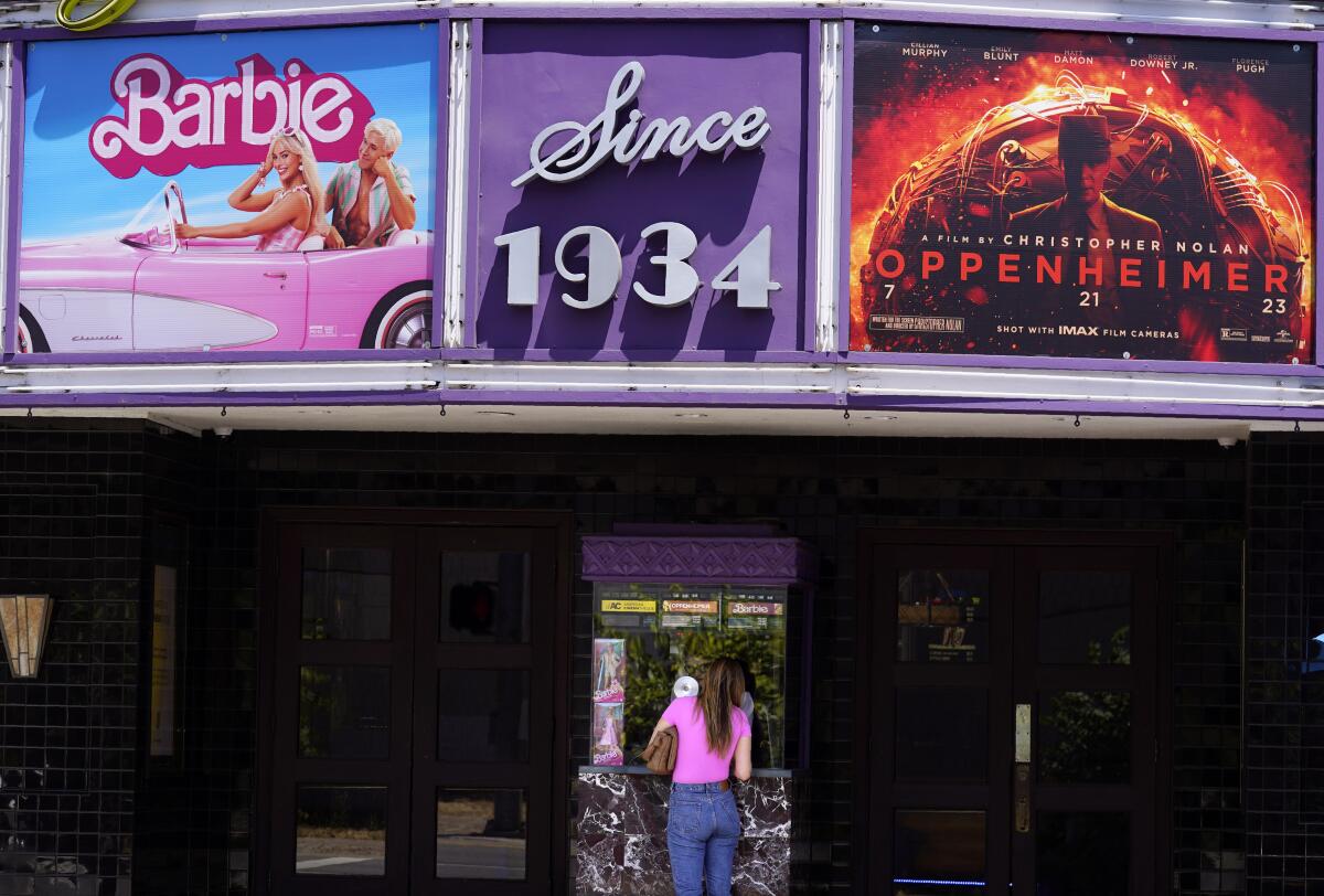 ARCHIVO - Una clienta compra un boleto de cine debajo de una marquesina con las películas "Barbie" 