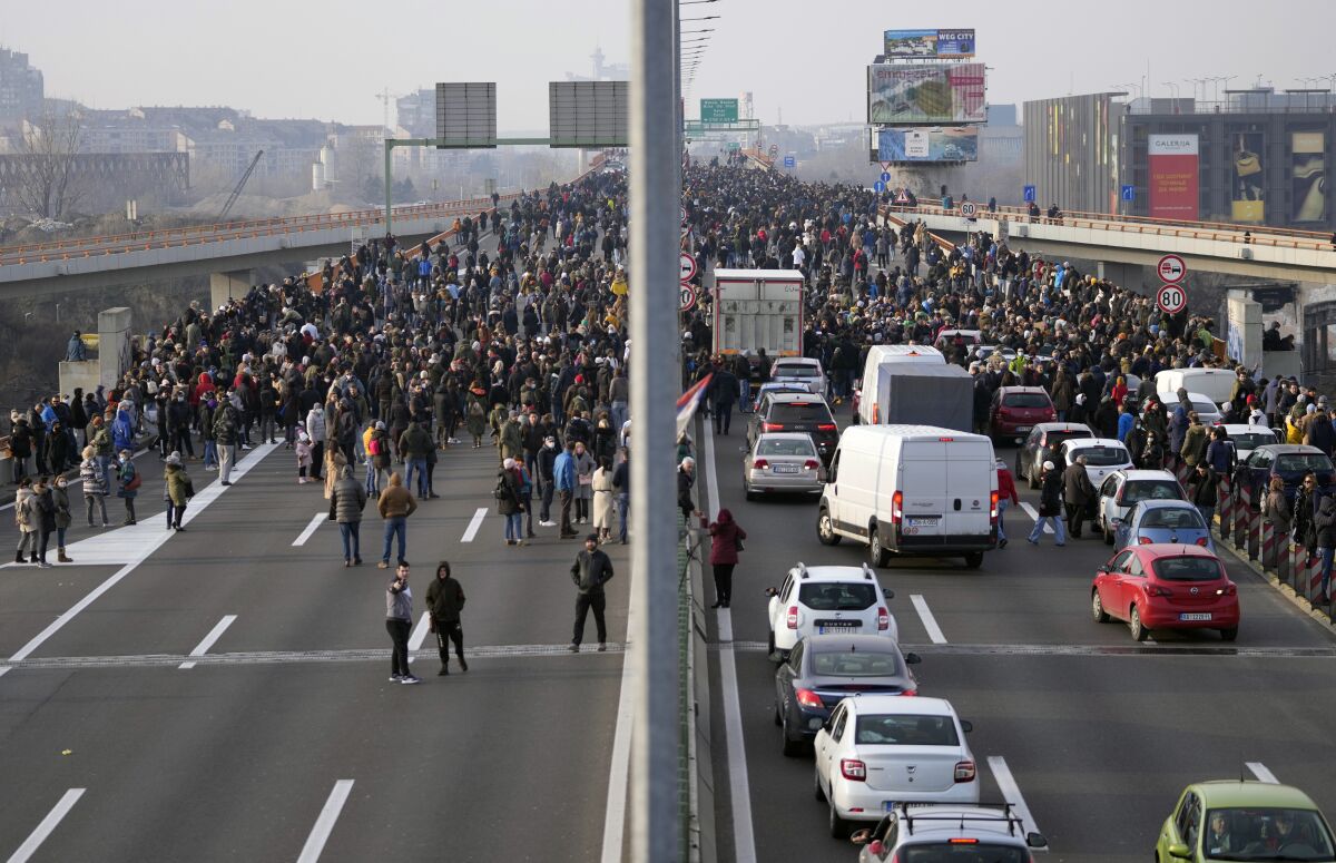 Protesters stand on the highway during a protest in Belgrade, Serbia, Saturday, Dec. 4, 2021. Thousands of protesters have gathered in Belgrade and other Serbian towns and villages to block roads and bridges despite police warnings and an intimidation campaign launched by authorities against the participants. Thousands of protesters have gathered in Belgrade and other Serbian towns and villages to block roads and bridges despite police warnings and an intimidation campaign launched by authorities against the participants. (AP Photo/Darko Vojinovic)