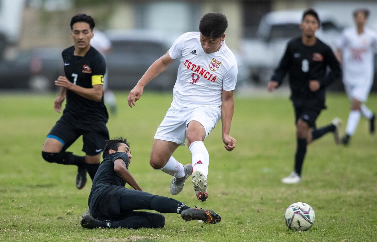 Estancia's Richard Cervantes leaps over a slide tackle from Los Amigos' Omar Martinez during a nonleague boys' soccer match.