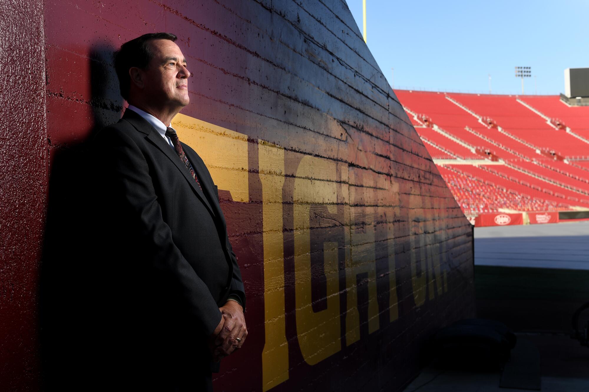 USC athletic director Mike Bohn wears a suit and stands inside the empty Coliseum.