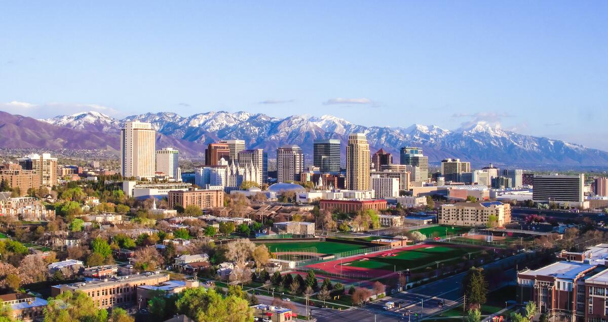 A city's skyline surrounded by snow-capped mountains.