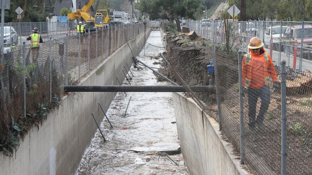 A member of the OC Public Works team looks for damage along part of the Laguna Canyon flood channel heavily damaged in the Feb. 14 storm.