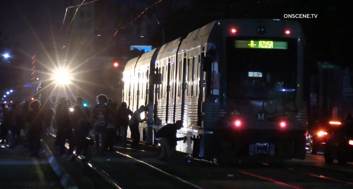 A group of people standing on tracks use spray paint to vandalize a halted train.