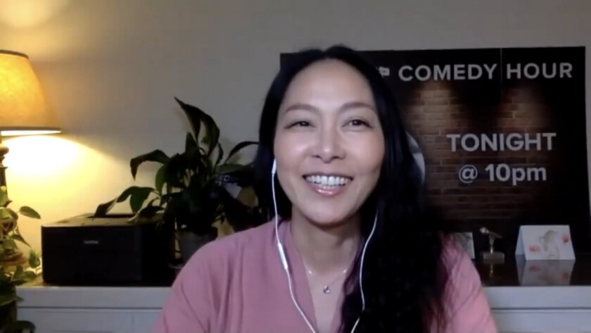 Kazu Kuzano sits in her home, wearing ear buds.