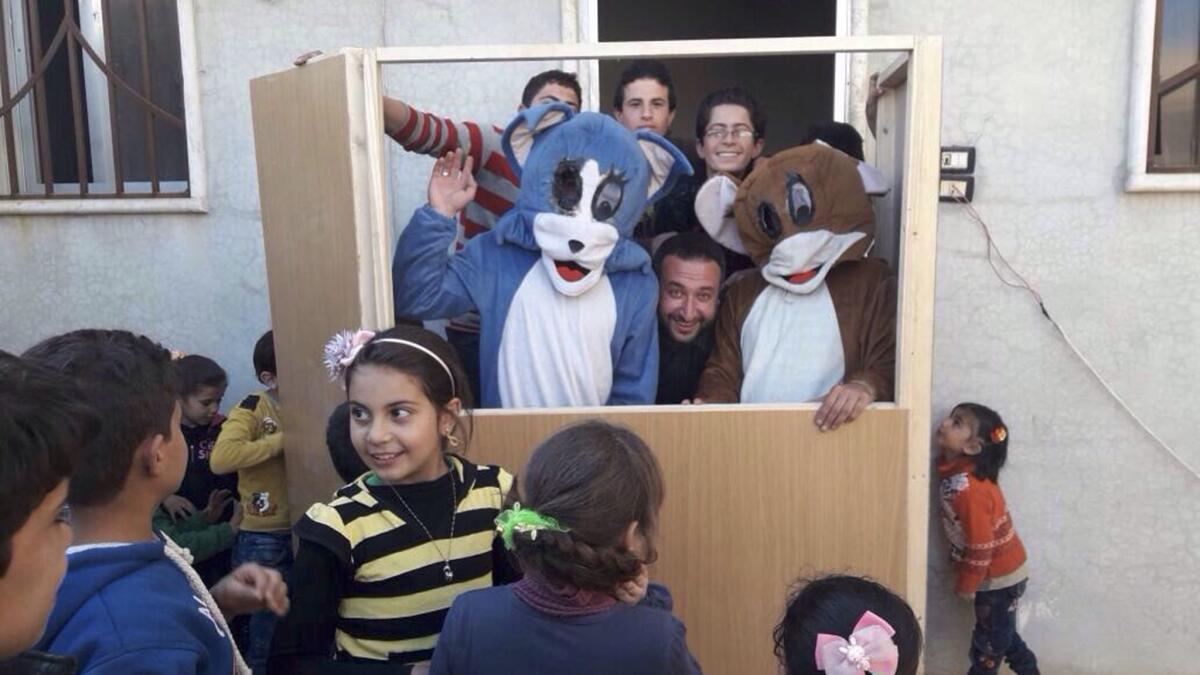 Members of the Saraqeb Youth Group entertain a young audience in Saraqeb, Syria, with a performance featuring the cartoon characters Tom and Jerry.