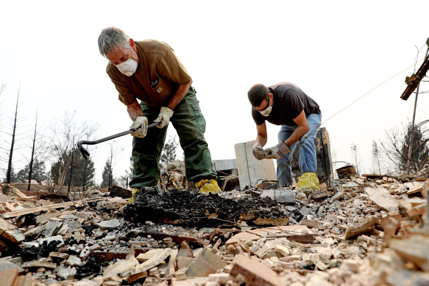 Dan Kissick, 60, left, shown with his son Jeff Kissick, searches the remains of his home on Kellinger Street on Saturday after the Carr fire hit Redding.