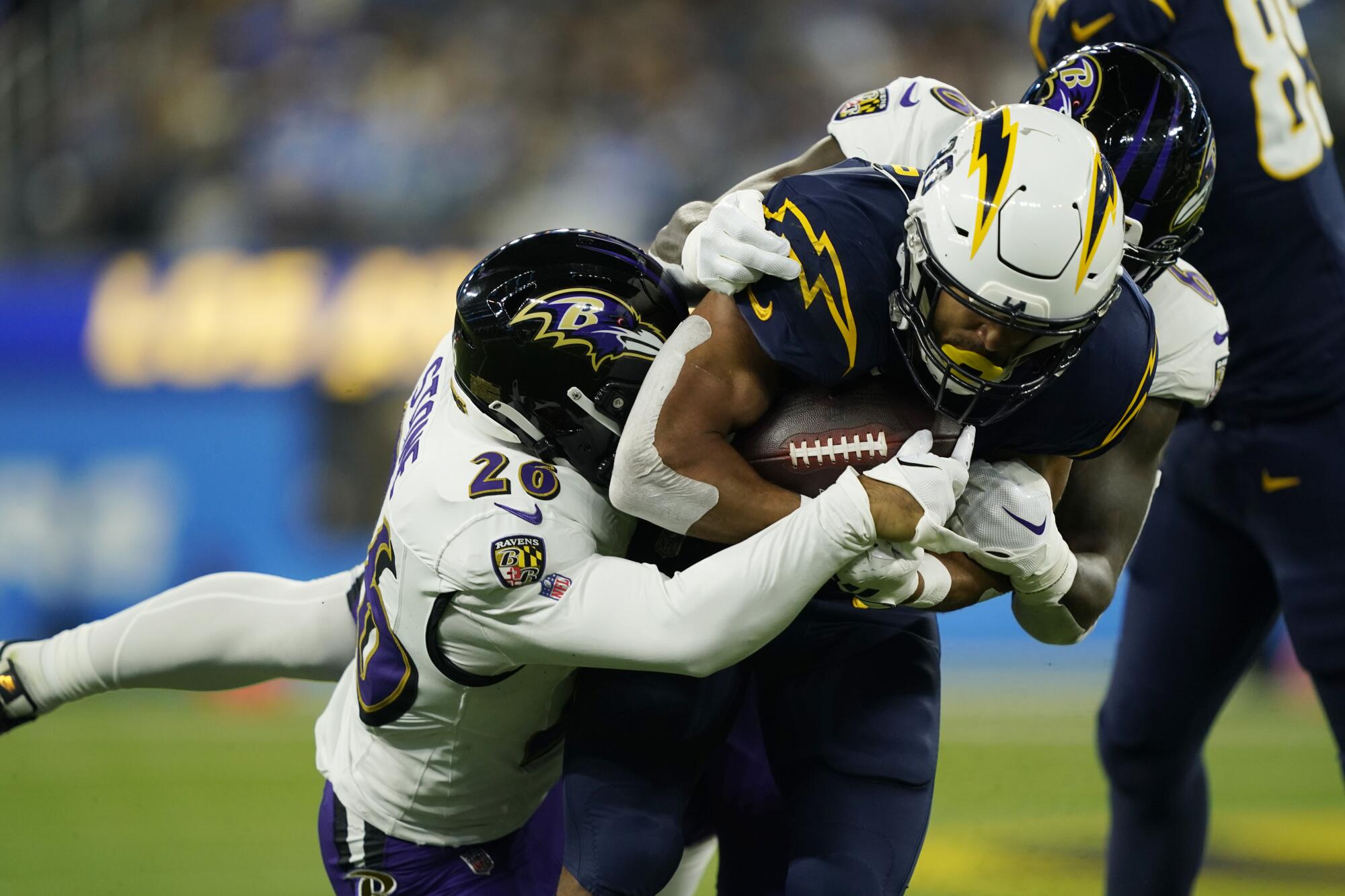 Chargers running back Austin Ekeler is tackled by Ravens safety Geno Stone and linebacker Patrick Queen 