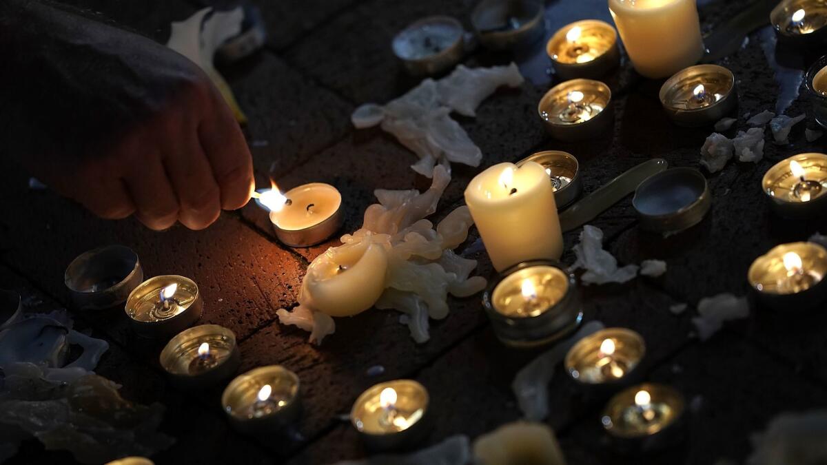 A man tends a candle at a vigil for those who died and were injured when a car plowed into a crowd of anti-racist counter-demonstrators in Virginia.