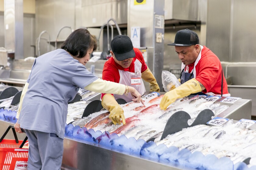 Seafood section staff helps a customer select the freshest fish at Arko Foods International.